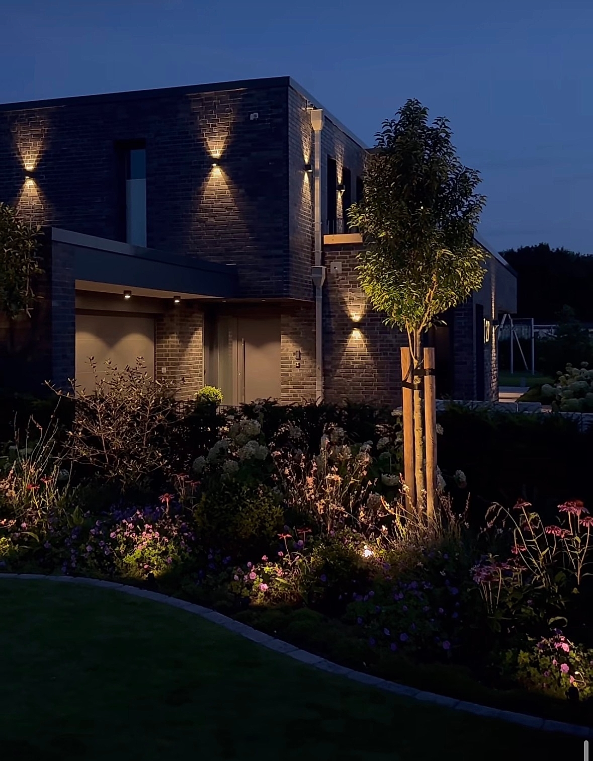 Sfeervolle tuin- en gevelverlichting bij een woning in de avond